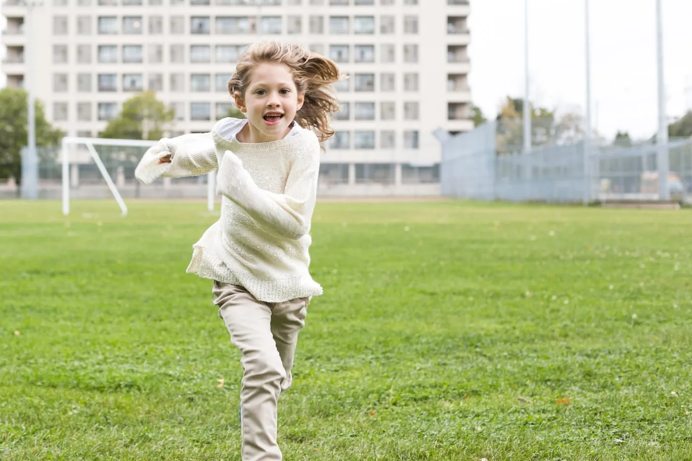 Une fillette court en riant sur un terrain
